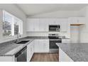 Bright kitchen with white cabinets, black appliances, granite countertops, and wood-look flooring at 5571 Creek Haven Way, Lakeland, FL 33810