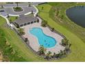 Aerial view of a community pool with a modern shape, featuring a cabana, lounge chairs, and well-kept landscaping at 1343 Foran Manor Rd, Haines City, FL 33844