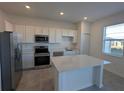 Modern kitchen with white cabinets, quartz countertops, and stainless steel appliances at 2499 Skyline Loop, Kissimmee, FL 34758