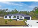 Modern home with white exterior, black accents, and a three-car garage at 39715 Royal Trails Road, Eustis, FL 32736