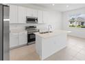 Bright kitchen with stainless steel appliances, center island, and modern white cabinetry at 507 Silver Palm Dr, Haines City, FL 33844