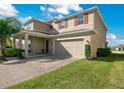 Two-story house with tan siding, brown door, and a two-car garage at 5317 Jubiloso Dr, St Cloud, FL 34771