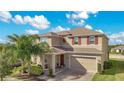 Two-story house with tan siding, brown door, and a two-car garage at 5317 Jubiloso Dr, St Cloud, FL 34771