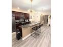 Modern kitchen with dark wood cabinets, granite counters, and stainless steel appliances at 8407 Riverdale Ln, Davenport, FL 33896