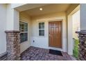 Front entry with a brown door, stone columns, and a brick walkway at 1490 Woodmont Blvd, Kissimmee, FL 34746