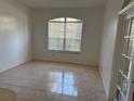 This living room has bright lighting from the window and tan, ceramic-look tile flooring at 63 York Ct, Kissimmee, FL 34758