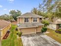 Two-story house with beige exterior, two-car garage, and surrounding homes at 8567 Baywood Vista Dr, Orlando, FL 32810