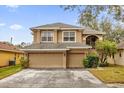 Two-story house with beige exterior, two-car garage, and lush landscaping at 8567 Baywood Vista Dr, Orlando, FL 32810