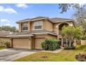 Two-story house with beige exterior, two-car garage, and mature shrubs at 8567 Baywood Vista Dr, Orlando, FL 32810