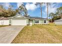 Newly built light green house featuring a white garage door and neat lawn at 10 Cedar Tree Dr, Ocala, FL 34472