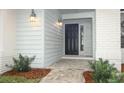 Modern black front door with updated light fixtures and walkway at 1633 Cedar Glen Dr, Apopka, FL 32712