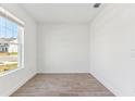 Well-lit room with wood-look tile floors and a large window providing a view of the neighborhood at 5000 Northern Dove Ave, Mount Dora, FL 32757