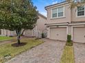 Tan two-story townhome with two-car garage and brick paver driveway at 8307 Fontera Dr, Davenport, FL 33896