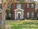 Up close view of a red brick two-story home with a well-manicured lawn and mature trees at 9501 Hempel Cove Blvd, Windermere, FL 34786