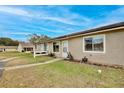 Exterior of tan condo building with a white door and small yard at 12340 Tavares Ridge Ln # 111, Tavares, FL 32778