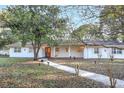 Charming ranch house with white brick facade and orange door at 3645 Mirror Lake Dr, Apopka, FL 32703