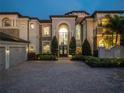 Elegant estate home at twilight features lush landscaping, a circular paver driveway, and a grand arched entry at 4089 Isabella Cir, Windermere, FL 34786