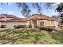 Tan house with a red door, lush landscaping, and a two-car garage at 7895 Saint Giles Pl, Orlando, FL 32835