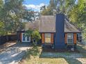 Eye-level exterior of a charming home with blue siding, wooden accents, and mature trees at 1254 Seminola Blvd, Casselberry, FL 32707