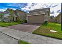 Two-story house with beige exterior, brick accents, and a two-car garage at 1726 Tree Shade Dr, Davenport, FL 33837