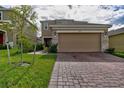 Two-story house with a beige exterior, brick accents, and a two-car garage at 1726 Tree Shade Dr, Davenport, FL 33837