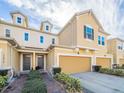 Tan townhome with a two-car garage and landscaped front at 17454 Chateau Pine Way, Clermont, FL 34711