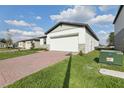 Single-story home with a red brick driveway, green lawn, and a two-car garage in a sunny neighborhood at 2307 White Tail St, Davenport, FL 33837