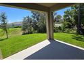 Relaxing covered porch overlooking a lush green backyard and mature trees on a sunny day at 2798 Portadown St, Ormond Beach, FL 32174