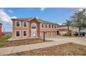 Tan two-story house with a three-car garage and expansive view at 3433 Glossy Leaf Ln, Clermont, FL 34711