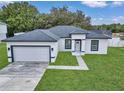 Newly built home with gray roof, white exterior, and a paved driveway at 3999 Sw 129Th St, Ocala, FL 34473