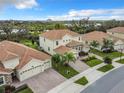 Aerial view of a neighborhood featuring similar homes with tile roofs and well-manicured lawns near a lake at 8886 Fallen Oak Dr, Davenport, FL 33896