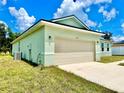 Side view of a new light green house with a beige two-car garage at 2645 Sw 155Th Ln, Ocala, FL 34473