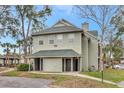 Two-story condo exterior with green siding, covered entrances and mature trees at 6034 Westgate Dr # 202, Orlando, FL 32835