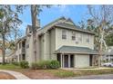 Two-story condo exterior with green siding, a covered entrance, and lush landscaping around the building at 6034 Westgate Dr # 202, Orlando, FL 32835