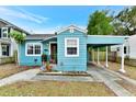 Charming bungalow with light blue exterior, carport, and landscaped yard at 1300 E Kaley St, Orlando, FL 32806