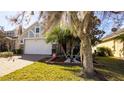 House exterior showcasing a lush lawn, mature trees, and brick accents at 16036 River Pointe Ct, Orlando, FL 32828