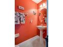 Small half-bathroom with pedestal sink and orange walls at 16583 Cedar Crest Dr, Orlando, FL 32828