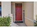 Red front door with welcome mat and surrounding greenery at 3666 Maidencain St, Clermont, FL 34714