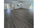Open living area with grey wood-look floors, kitchen, and access to backyard at 620 Heraldo Ct, Kissimmee, FL 34758