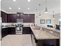 Modern kitchen featuring dark wood cabinets, granite countertops, and stainless steel appliances at 9218 Shepton St, Orlando, FL 32825