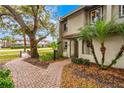 Exterior side view of the townhome with lush landscaping, a brick walkway, and mature trees at 1007 Baseball And Boardwalk Ct, Kissimmee, FL 34746