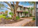 Exterior of a tan townhome featuring a red tile roof, brick walkway, and mature landscaping at 1007 Baseball And Boardwalk Ct, Kissimmee, FL 34746