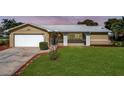 Tan brick ranch home with a white garage door and landscaped lawn at 2207 Winter Woods Blvd, Winter Park, FL 32792