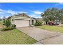 Landscaped one-story house with a beige garage door and a spacious driveway at 2711 Angel Mist Ct, Mascotte, FL 34753