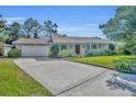 Inviting single-story home with a brick facade, an ample driveway, mature landscaping, and blue shutters at 4130 Floralwood Ct, Orlando, FL 32812