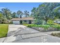 Inviting single-story home with a brick facade, an ample driveway, mature landscaping, and blue shutters at 4130 Floralwood Ct, Orlando, FL 32812