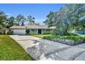 Inviting single-story home with a brick facade, an ample driveway, mature landscaping, and blue shutters at 4130 Floralwood Ct, Orlando, FL 32812