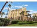 Multi-story building with yellow facade, palm trees, and lush landscaping at 8101 Resort Village Dr # 31308, Orlando, FL 32821