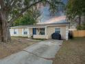 Tan house with blue door, white shutters, and a large tree in the front yard at 1404 Adair St, Ocoee, FL 34761