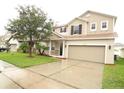 Two-story house with beige siding, brown roof, and a two-car garage at 15269 Galbi Dr, Orlando, FL 32828